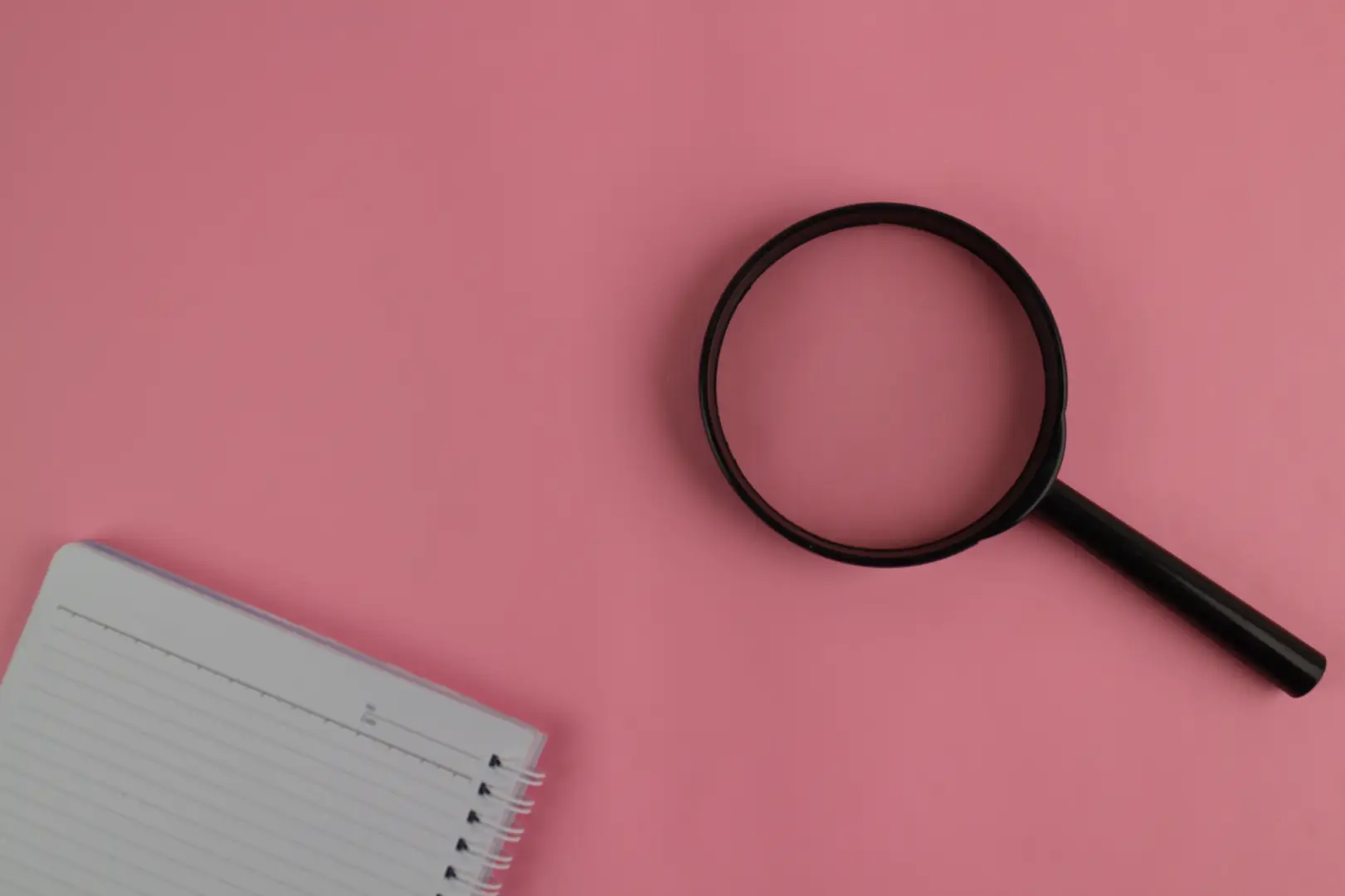 Magnifying glass on a pink background.
