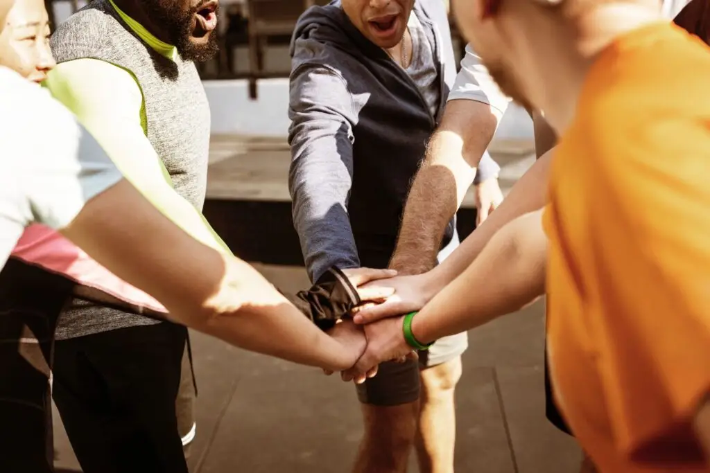 a team high five each other standing in a circle showcasing customer experience collaboration.