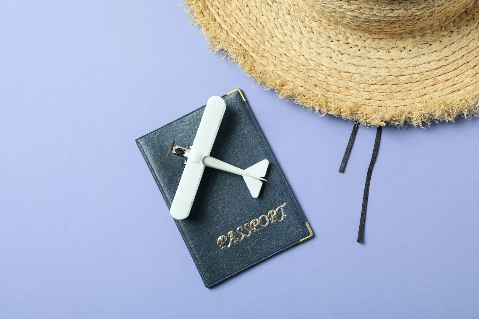 A straw hat, passport and a model airplane, set to show that the article includes a travel and vacation customer journey map.