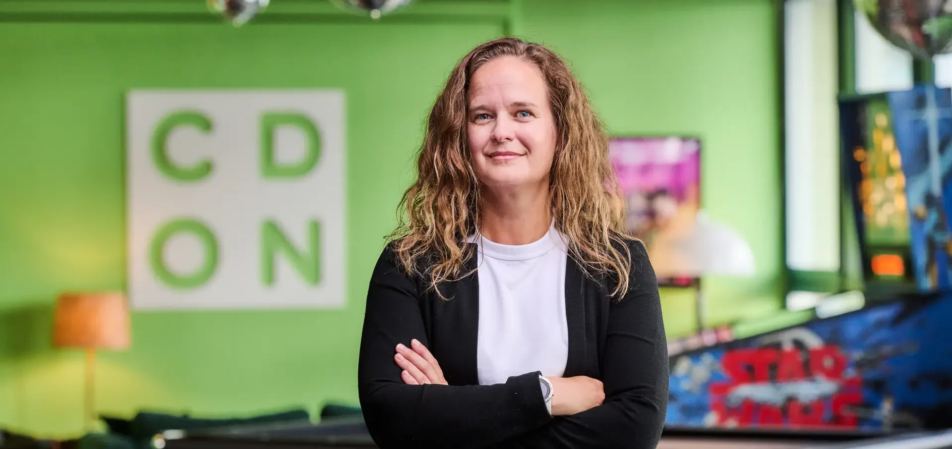 Kattis Åström standing next to a green wall. The picture illustrates the CDON Customer Experience interview that we conducted.