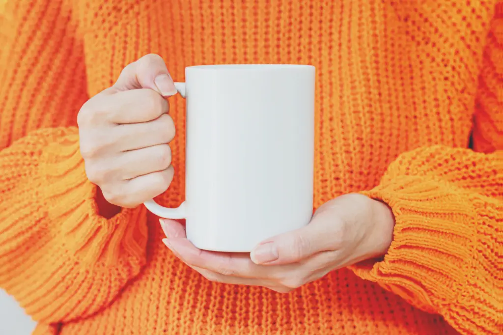 A woman in orange sweater holding a white cup illustrating a e-commerce persona with a specifik need (the go-getter)